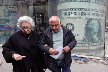 MATA WANG TERJEJAS: Warga senja keluar dari pejabat pertukaran wang di Kahirah, Mesir berlatarkan imej dolar Amerika kelmarin tatkala ramai warga negara itu dibelenggu masalah kewangan. - Foto EPA-EFE