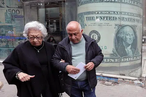 MATA WANG TERJEJAS: Warga senja keluar dari pejabat pertukaran wang di Kahirah, Mesir berlatarkan imej dolar Amerika kelmarin tatkala ramai warga negara itu dibelenggu masalah kewangan. - Foto EPA-EFE