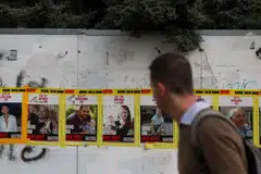 Seorang lelaki melintas di hadapan poster tebusan Encik Yarden Bibas dan dua anaknya, Shiri Bibas dan Kfir Bibas, yang dipasang di tepi jalan raya di Baitulmakdis.