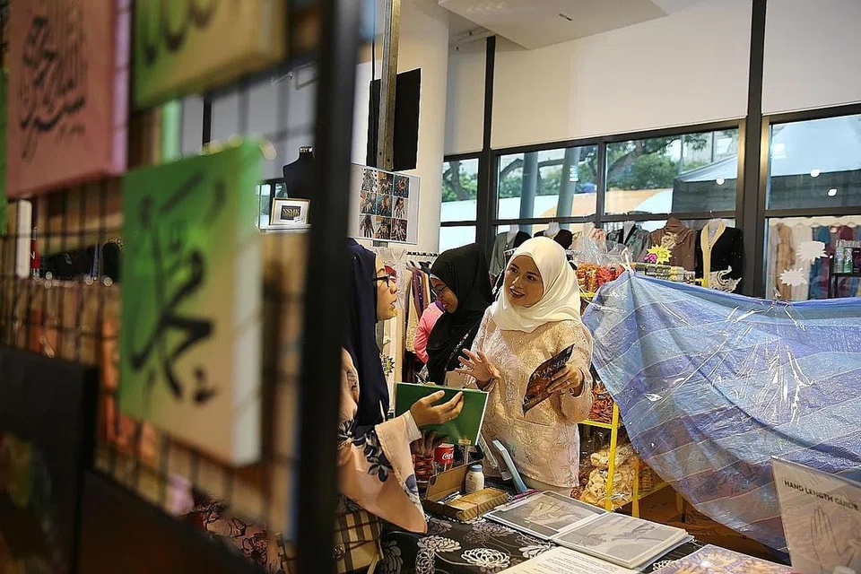 PASAR LAMBAK: Cik Nurlida Yusof (tudung putih) meninjau pasar lambak anjurannya di Wisma Geylang Serai. - Foto BH oleh BENJAMIN SEETOR