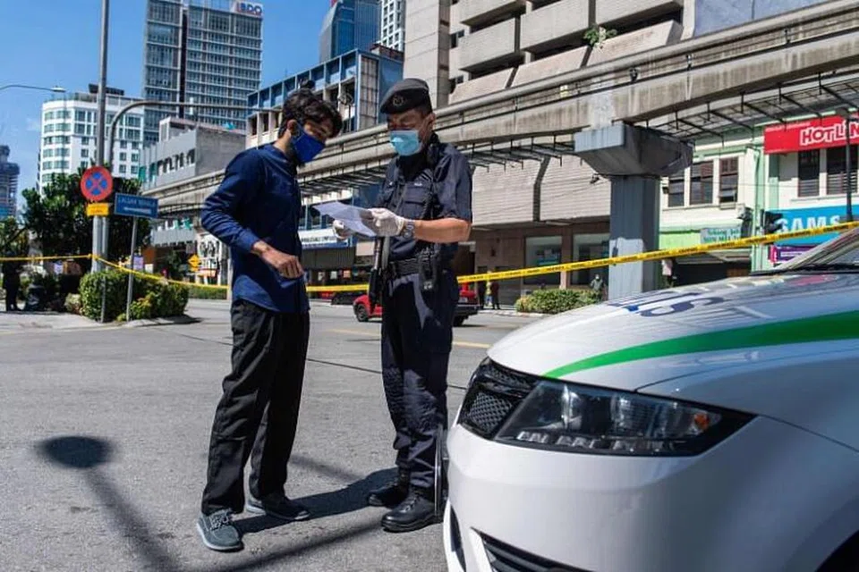 Gambar diambil pada 25 Mac, 2020,menunjukkan seorang pegawai polis memeriksa dokumen perjalanan di Kuala Lumpur. 