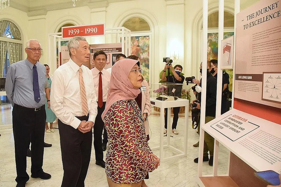 LIHAT PAMERAN: Presiden Halimah ditemani Encik Lee (tengah), Encik Goh (paling kiri) dan Menteri Pendidikan Encik Chan Chun Sing (belakang) semasa melihat pameran yang menyorot sejarah dan perkembangan CPIB sempena ulang tahun ke-70 biro itu malam tadi. - Foto BH oleh DESMOND WEE
