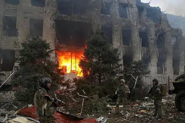 ENGGAN SERAH DIRI: Anggota perkhidmatan tentera pro-Russia, termasuk pejuang unit pasukan khas Chechen, berdiri di hadapan sebuah bangunan pentadbiran yang musnah semasa konflik Ukraine-Russia di bandar pelabuhan selatan Mariupol, Ukraine. - Foto REUTERS