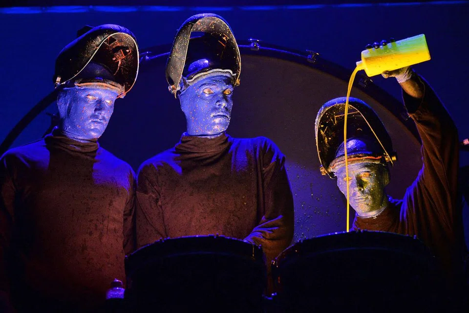 USIK-MENGUSIK: Tiga jejaka biru Blue Man Group ini menuang cat kuning pada dram yang kemudian dipalu dalam aksi melucukan yang membuka tirai persembahan. - Foto AFP