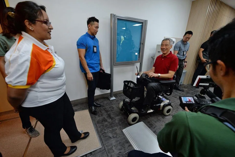 PELBAGAI KHIDMAT: Perdana Menteri Lee Hsien Loong yang hadir semasa sesi pelancaran Kampus Hospital Sengkang sedang mencuba kerusi roda bermotor yang terdapat di Kampus SKH. - Foto WANBAO