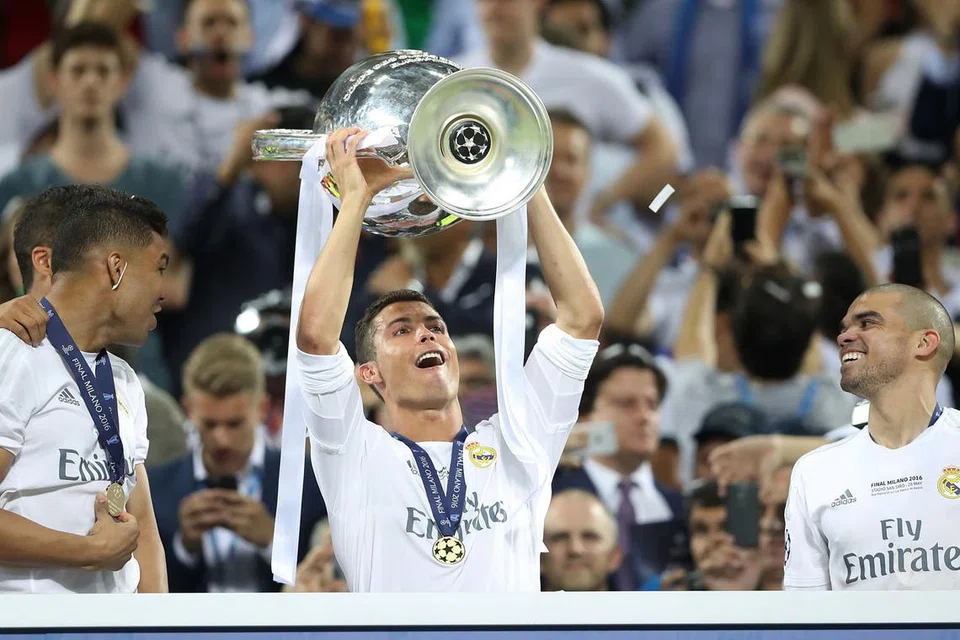 RAIH KEJAYAAN: Bintang Real Madrid, Cristiano Ronaldo (tengah), menjulang Piala Liga Juara-Juara di Stadium San Siro, Milan, Italy, kelmarin. Ronaldo mejadi penjaring gol terbanyak Liga Juara-Juara musim ini.