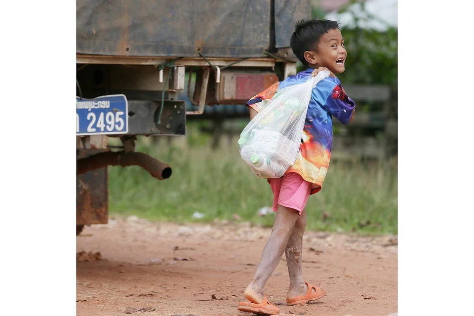 BANTUAN UNTUK KELUARGA: Kanak-kanak gembira mendapat bekalan bantuan bagi keluarga mereka di pusat pemindahan Sanamxay.