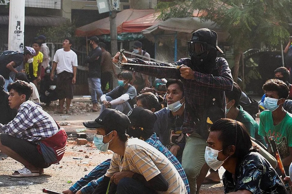 LASTIK AMARAH: Seorang penunjuk perasaan dilihat melepaskan 'peluru' berupa kerikil dalam satu tunjuk perasaan di Yangon dalam satu pertempuran dengan pihak berkuasa yang lengkap bersenjata kelmarin. - Foto REUTERS 