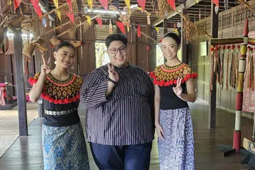 KENALI BUDAYA IBAN: Penulis (tengah) bersama para penari dari suku kaum Iban di dalam sebuah replika rumah panjang Iban. 