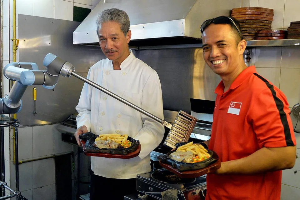 TUKANG MASAK CANGGIH: Robot yang dihasilkan oleh syarikat Encik Kahar Hassan (kanan) berjaya membantu pemilik restoran Mak's Place The Hawkerant, Encik Muhammed Feroz Mak Kok Leong (kiri), meningkatkan daya penghasilan restorannya. - Foto IMAN ALIF