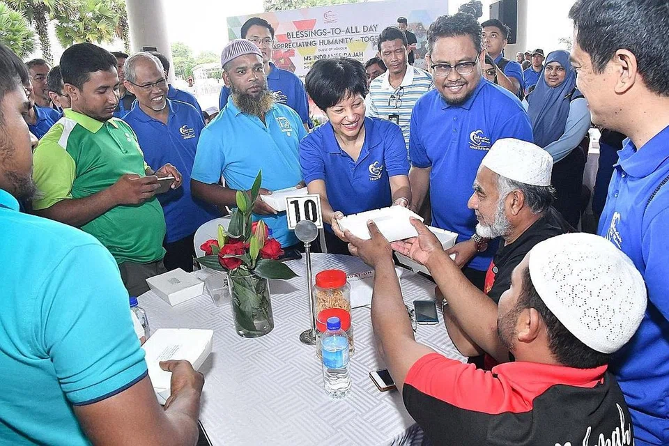 AGIH MAKANAN: Cik Indranee Rajah (tengah) menghulurkan sebungkus makanan kepada pekerja asing di Hari RLA yang berlangsung di Bendungan Marina semalam. Turut bersama ialah Encik Masagos Zulkifli Masagos Mohamad (dua dari kiri). - Foto MUIS
