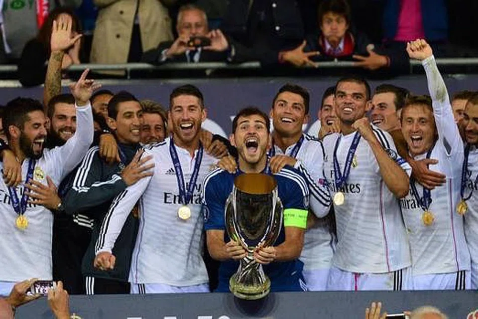 YANG PERTAMA DALAM GENGGAMAN: Kapten yang juga penjaga gawang Real Madrid, Iker Casillas, cuba menjulang trofi Piala Super dengan dikerumuni rakan-rakannya selepas menewaskan Sevilla 2-0 di Stadium Cardifff City kelmarin. - Foto AFP