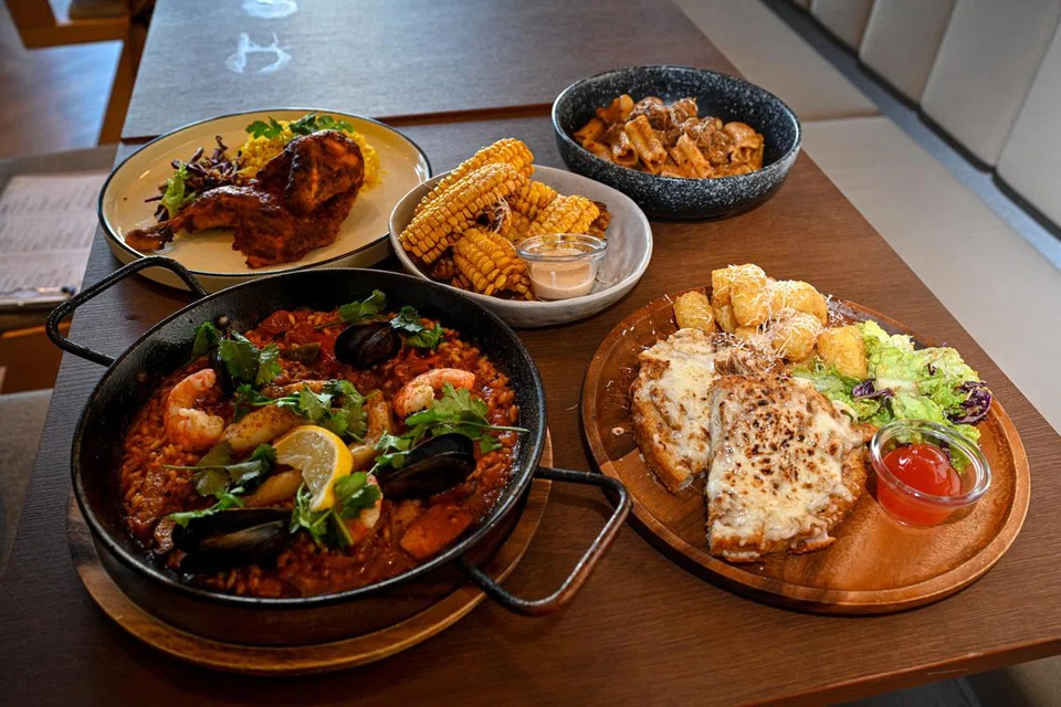 Brunch @ Legundi menyediakan (dari kiri bawah, mengikut putaran jam) hidangan nasi kunyit dengan makanan laut, ‘Paella De Marisco’; Nasi Ayam Kuning; potongan daging bersama jagung, ‘Corn Ribs’; Pasta Rendang; dan Roti John.
