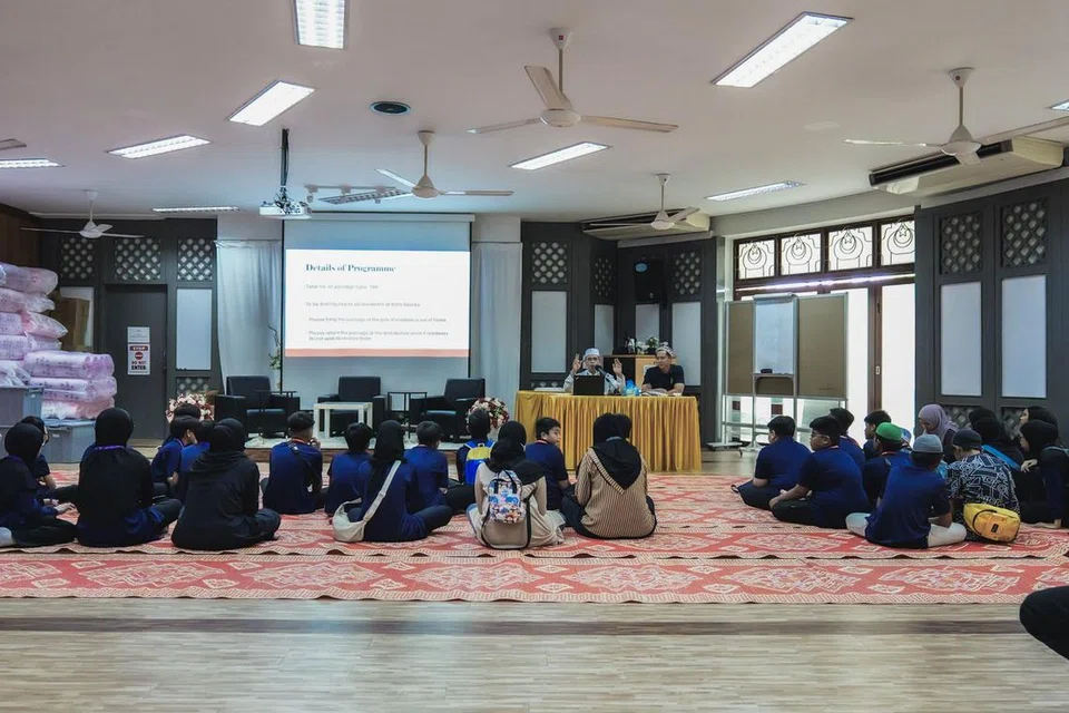 Ustaz Mohamad Noor Samat (duduk di kerusi, kiri) bersama Ustaz Muhamad Irwan Saian, memberi taklimat kepada sukarelawan masjid yang juga merupakan pelajar mingguan aLIVE, sebelum acara pengagihan bubur kepada penduduk pada Ramadan 2024.