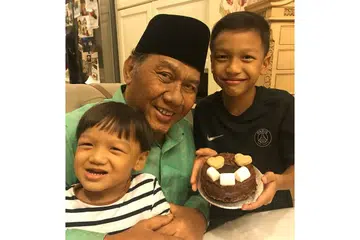 PENYAYANG: Allahyarham Idris Mohd Yusof menyambut ulang tahunnya ke-72 bersama cucunya Aidan Irfan (kanan), yang membuat kek untuknya, dan Rayan Irfan. - Foto ihsan ANDY IDRIS