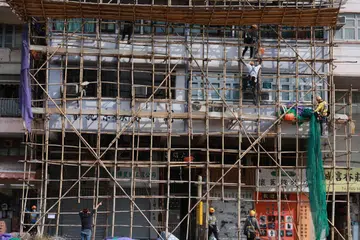 Para pekerja menanggalkan jaring perancah di daerah Sham Shui Po di Hong Kong, China, pada 5 Disember 2025. Susulan kebakaran maut di Wang Fuk Court di daerah Tai Po, pihak berkuasa mengeluarkan arahan seluruh kota untuk menanggalkan jaring mudah terbakar yang digantung pada bangunan yang sedang dibaiki atau diubah suai.