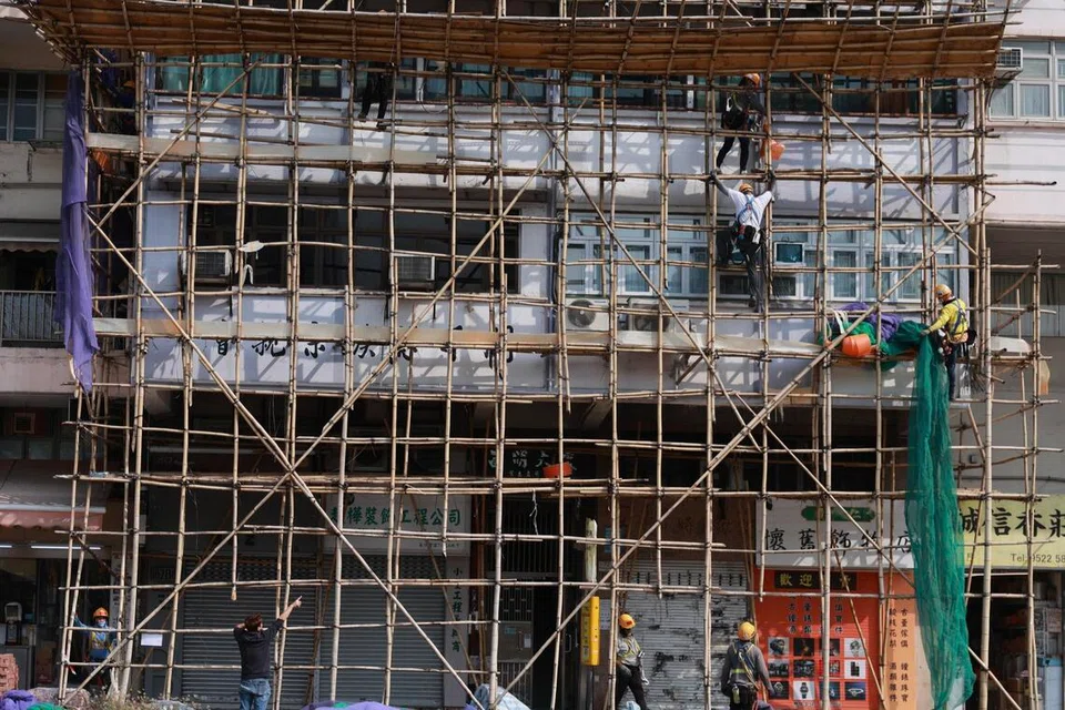 Para pekerja menanggalkan jaring perancah di daerah Sham Shui Po di Hong Kong, China, pada 5 Disember 2025. Susulan kebakaran maut di Wang Fuk Court di daerah Tai Po, pihak berkuasa mengeluarkan arahan seluruh kota untuk menanggalkan jaring mudah terbakar yang digantung pada bangunan yang sedang dibaiki atau diubah suai.