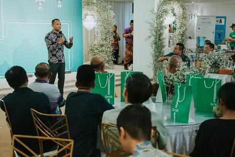 TINGKATKAN DIRI: Encik Mohd Fahmi Aliman (berdiri) berucap di hadapan 180 pekerja Grab semasa acara 'Eid & Eat 2023' di City Plaza pada Rabu. - Foto FORUM BELIA MUSLIM