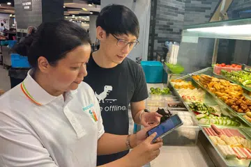 Sukarelawan menunjukkan pengguna cara menggunakan aplikasi Price Kaki untuk membandingkan harga dan berkongsi tawaran. 