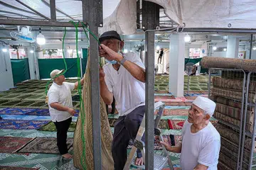 GOTONG-ROYONG: Encik Yassin (tengah) giat membuat persiapan bersama relawan lain di kolong Blok 450 Tampines Street 42 sebelum ketibaan jemaah bagi solat tarawih pada Rabu. - Foto BH oleh SHAFIQ APANDI