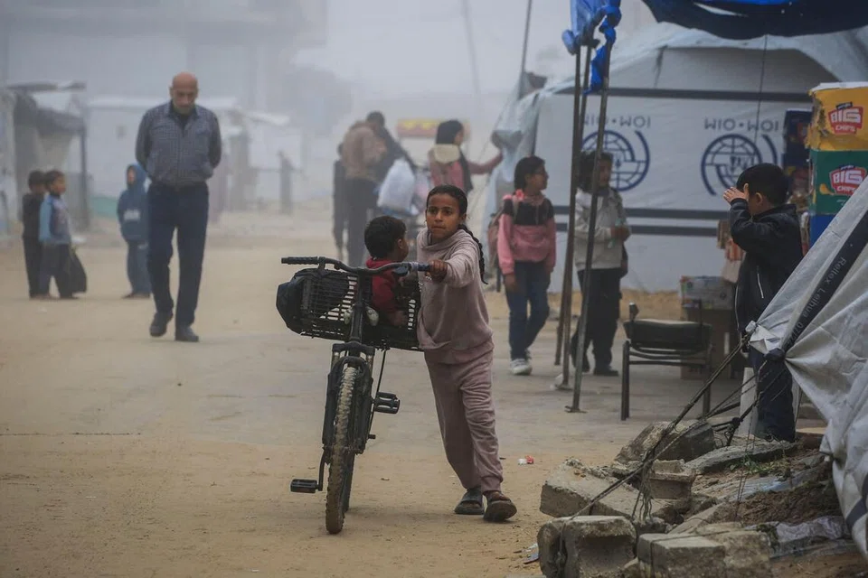 Seorang kanak-kanak perempuan Palestin menolak basikal melalui sebuah kem perpindahan di Khan Younis, di Jaluran Gaza, pada 10 Februari 2026. Gencatan senjata yang diterajui Amerika Syarikat dan berkuat kuasa sejak Oktober lalu bertujuan menghentikan pertempuran antara Israel dengan Hamas susulan serangan kumpulan itu pada Oktober 2023 telah mengurangkan tahap pengeboman dan pertempuran.