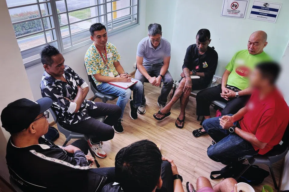 Ketua pekerja perkhidmatan sosial program ‘Brotherhood’, Encik Ben Ang (tiga dari kiri), mengadakan sesi perbincangan bersama peserta yang digalak mengongsi kisah peribadi mereka. Wajah salah seorang pegawai yang bertugas bagi membimbing peserta telah dikaburkan bagi melindungi identitinya sementara baki peserta bersetuju gambar mereka diambil. 