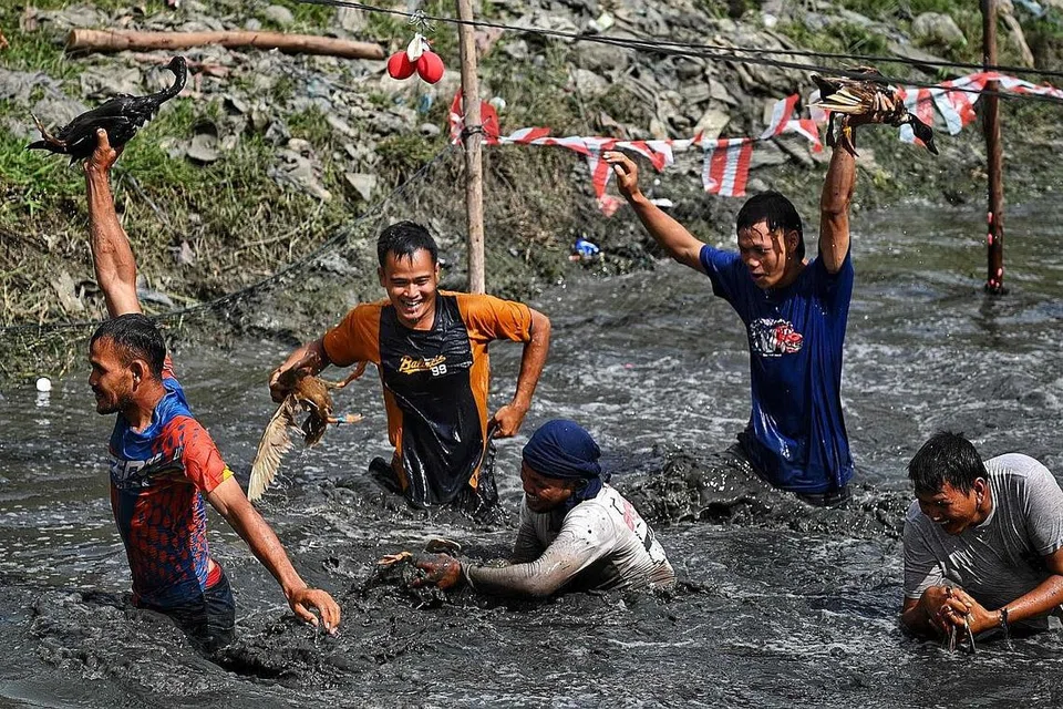 SEMANGAT SAMBUT KEMERDEKAAN: Sekumpulan remaja (gambar kiri) asyik bergelumang dalam sungai berlumpur dalam sukan air sempena menyambut ulang tahun kemerdekaan ke-77 Indonesia, di Banda Aceh. - Foto AFP