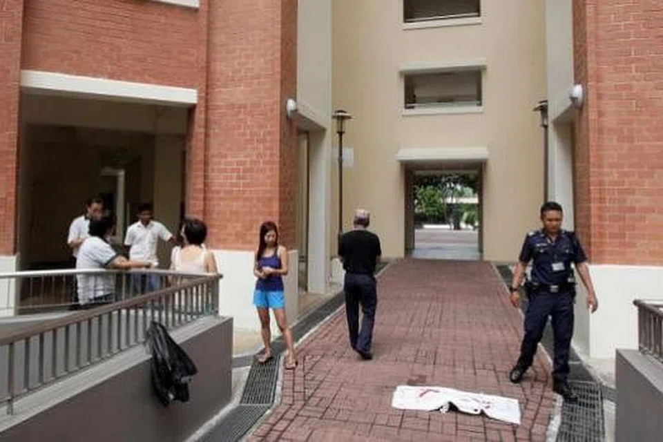 Pegawai polis dan penduduk di kaki sebuah blok di Yishun di mana seekor kucing ditemui mati. Gambar SHIN MIN