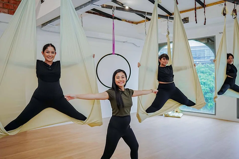 Cik Raidah Syafiqah binte Ahmad (tengah) menyedari beliau mempunyai bakat mengajar yoga udara dengan cara yang paling berkesan sehingga menjadikan pelajarnya berani mencuba aksi-aksi menarik.
