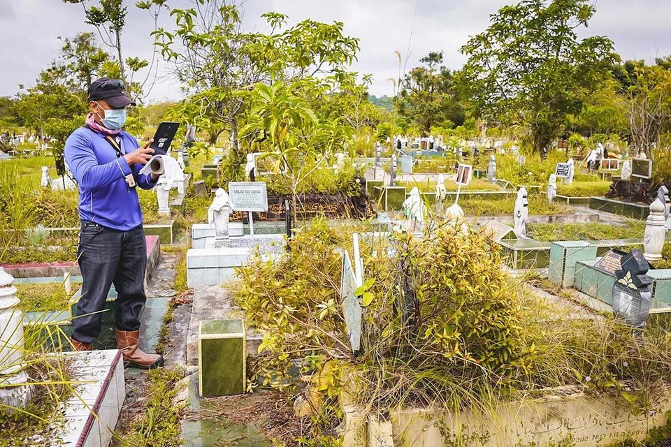 MUDAHKAN WARIS KENAL PASTI: Seorang pegawai lapangan Wareesan Management, Encik Muhammad Fadzli Adnan, mengambil gambar kubur yang terjejas oleh fasa terbaru penggalian dan pengebumian semula, bagi memudahkan waris mengesahkan kubur ahli keluarga mereka itu dalam talian. - Foto BH oleh NUR DIYANA TAHA 