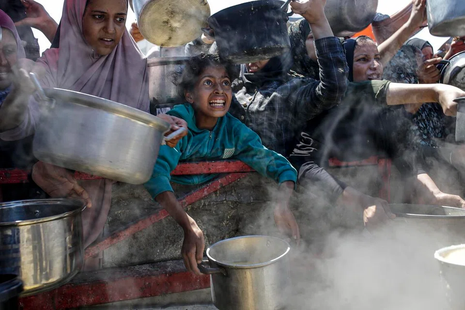 (Foto sisipan) Penduduk Palestin yang kehilangan tempat tinggal, termasuk kanak-kanak, dengan periuk di tangan berkumpul untuk menerima makanan di Bandar Gaza, Jaluran Gaza, pada 4 Ogos 2025