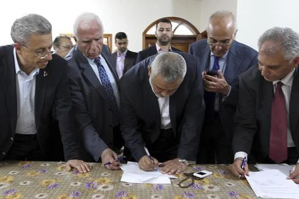 TANDATANGANI PERJANJIAN: Encik Ismail Haniyeh, Perdana Menteri Hamas (tengah), dan Encik Azzam al-Ahmad, ketua pemimpin kanan Fatah (kedua dari kiri), di upacara menandatangani perjanjian perpaduan antara kedua-dua pihak. - Foto REUTERS
