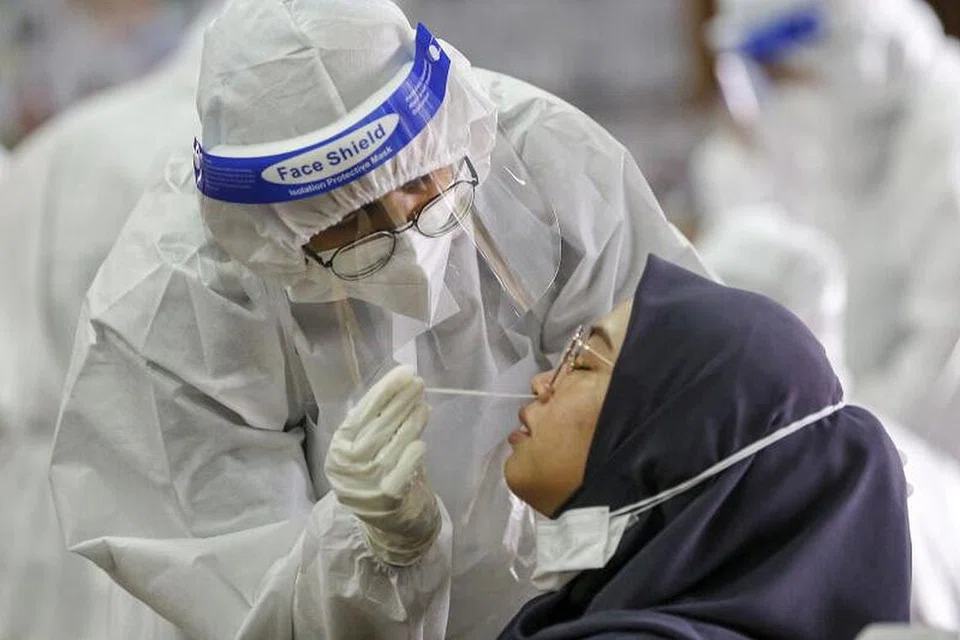 KEADAAN BELUM PULIH: Seorang wanita menjalani ujian swab bagi mengenal pasti jangkitan Covid-19 di dalam kereta di Kuala Lumpur. Kes harian baru di Malaysia kini mencecah melebihi 7,000 kes. - Foto EPA-EFE/AHMAD YUSNI 