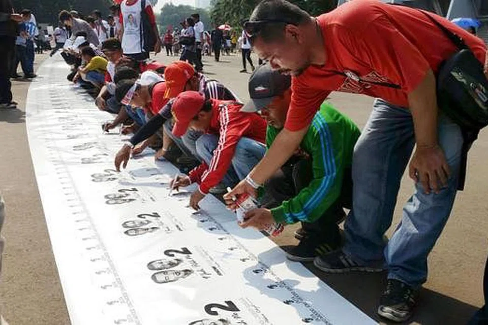 BERI SOKONGAN: Ribuan penyokong pasukan Jokowi-JK menandatangani kain rentang yang dibentangkan di luar Stadium Gelora Bung Karno, Senayan, sebelum berlangsungnya konsert 'Salam Dua Jari' kelmarin. - Foto CHAIRUL FAHMY HUSSAINI