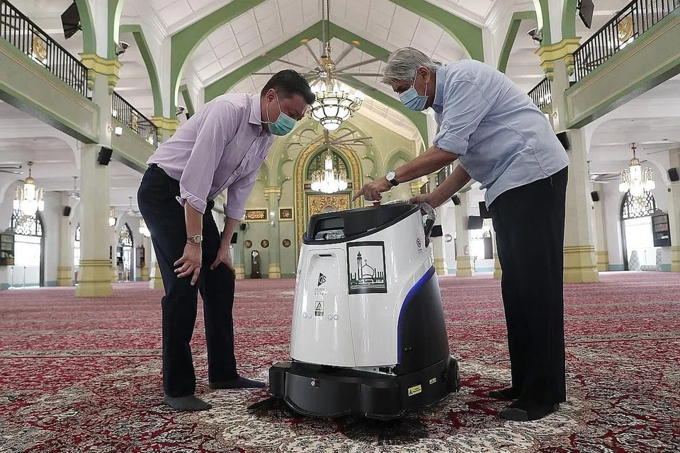 MUDAHKAN KERJA PEMBERSIHAN: Pengarah Bestway Cleaning Services, Encik Fabian Tang (kiri), menunjukkan kepada Encik Mohamed Salleh Patail (kanan) bagaimana cara menggunakan vakum robot 'Ecobot Sweep 40'. - Foto BH oleh KELVIN CHNG
