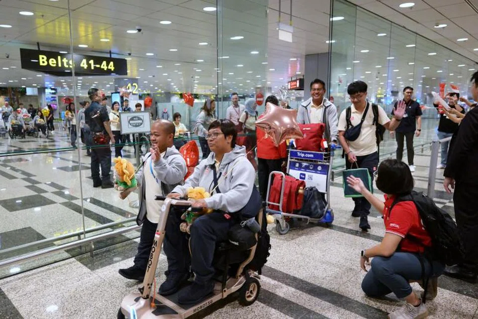 Pelontar peluru para Singapura, Diroy Noordin (kiri), dan atlet memanah para Singapura, Nur Syahidah Alim (kanan di alat bantuan mobiliti peribadi), mengukir senyuman dan memberi lambaian kepada penyokong sejurus sahaja tiba di Lapangan Terbang Changi pada 10 September. 