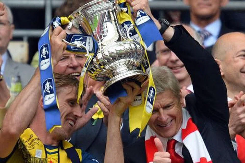 KEJAYAAN BERSEJARAH: Pengurus Arsenal, Arsene Wenger (kanan), menjulang mahkota Piala FA untuk kali keenam sejak beliau memimpin kelab Arsenal itu. Bersamanya ialah pemain pertahanan pasukan, Nacho Monreal. - Foto AFP