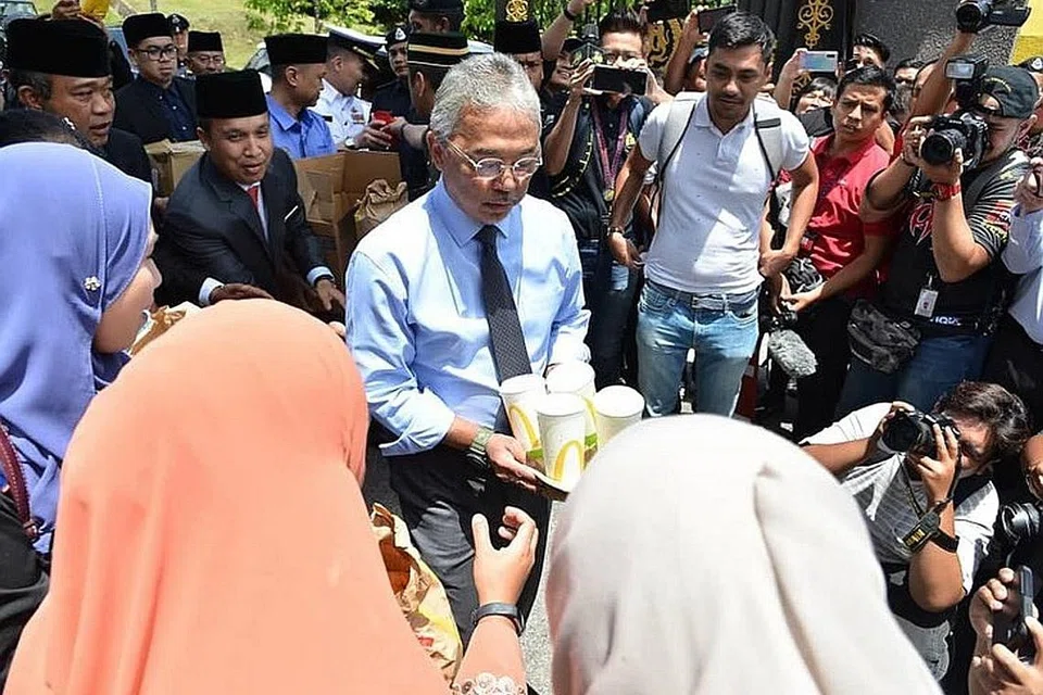 AGIHKAN MAKANAN: Yang di-Pertuan Agong mengagih-agihkan sendiri minuman dan makanan kepada wakil-wakil media yang bertugas di pintu 2 Istana Negara. Mengenai proses temu bual, ia akan dilakukan sehingga Agong berpuas hati ada parti yang mempunyai majoriti untuk membentuk kerajaan dan mengenal pasti perdana menteri kelapan. - Foto FACEBOOK ISTANA NEGARA