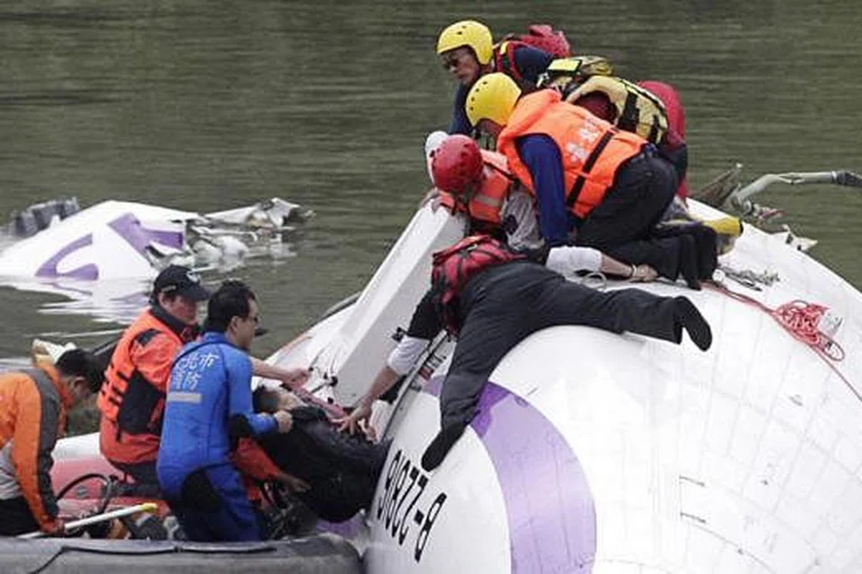 DAPAT DISELAMATKAN: Pasukan penyelamat mengeluarkan seorang penumpang daripada pesawat TransAsia Airways yang terhempas di sungai di Taipei City, semalam. - Foto REUTERS