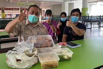 IFTAR AMAL: Ustaz Mohd Zakir Isahak bersama beberapa tukang masak belia dari Malaysia yang bekerja di kantin madrasah itu bersama sajian makanan iftar yang mereka sediakan. - Foto MADRASAH ALJUNIED AL-ISLAMIAH
