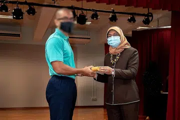 LEMBARAN BARU: 'Adam' menerima Anugerah Emas bagi NYAA daripada Presiden Halimah Yacob di Institusi Tanah Merah 1 semalam. Bertekad memulakan lembaran baru 'Adam' telah menyertai Sekolah Penjara dan melibatkan diri dalam NYAA. - Foto PERKHIDMATAN PENJARA SINGAPURA (SPS)