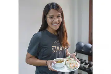 SIAPKAN MAKANAN LEBIH AWAL: Cik Aqilah menasihatkan pekerja yang bertugas mengikut giliran supaya membawa bekal makanan yang disiapkan sendiri supaya tidak terdesak membeli makanan yang mungkin kurang sihat yang dijual di tempat kerja. Kelihatan Cik Aqilah memegag sepiring gulungan Popia Udang Vietnam Segar Dengan Sos Kacang yang resipinya di kanan. - Foto BH oleh IQBAL FAIZAL