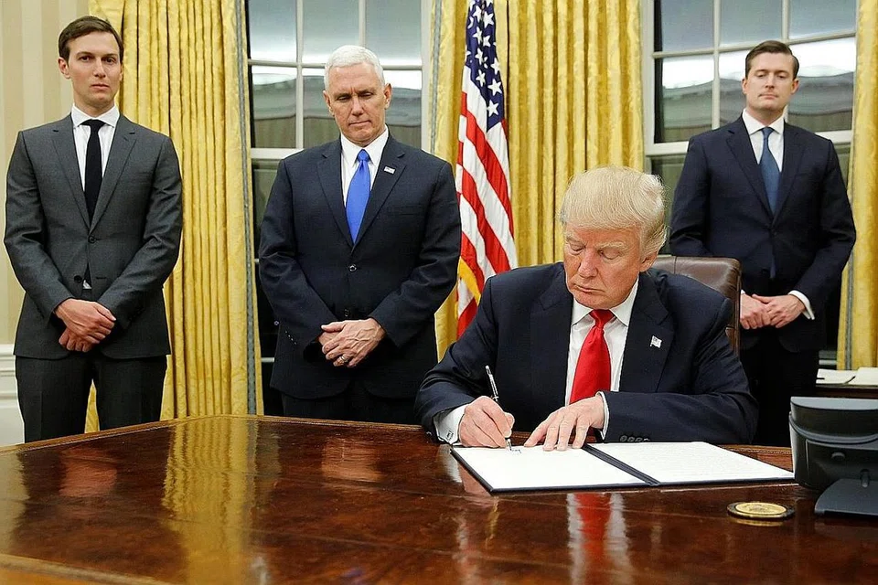 SEGERA BERTUGAS: Encik Donald Trump (duduk) menandatangi arahan eksekutifnya yang pertama di Pejabat Oval semalam dengan diperhatikan (dari kiri) Penasihat Kanan, Encik Jared Kushner; Naib Presiden Mike Pence; dan Setiausaha Kakitangan, Encik Rob Porter. - Foto REUTERS
