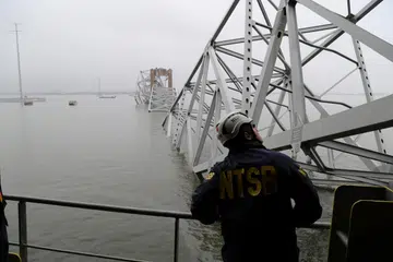 Seorang pekerja Lembaga Keselamatan Pengangkutan Kebangsaan (NTSB) melihat kapal kargo Dali, yang melanggar sehingga menyebabkan Jambatan Francis Scott Key, di Baltimore, Maryland, runtuh.