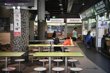 TERAP LANGKAH KESELAMATAN BARU: Tanda baru di tempat duduk di pusat penjaja di Our Tampines Hub yang membolehkan hingga lima orang duduk makan semeja, yang dibolehkan di bawah fasa kedua pembukaan. Makan di luar tidak dibenarkan semasa tempoh pemutus litar jangkitan dan pembukaan fasa pertama. - Foto BH oleh ARIFFIN JAMAR