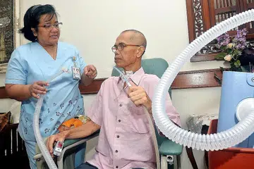 SOKONGAN JURURAWAT: Encik Sahari Musa mendapat sokongan jururawat amali lanjutan atau 'advanced practice nurse' (APN) Hospital Tan Tock Seng, Cik Kamilah Sheikh Jabin, yang datang ke rumah beliau untuk memantau keadaan kesihatannya, selain memastikan mesin penyokong pernafasan beliau dalam keadaan baik. - Foto KHALID BABA
