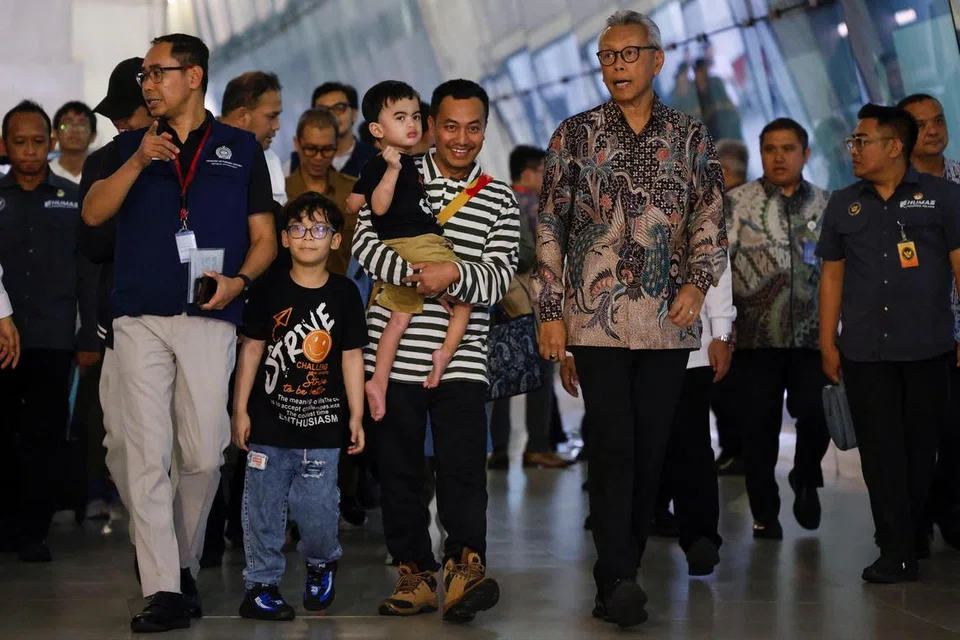 Encik Ali Murtado mendukung anak lelakinya sambil berjalan bersama Ketua Pengarah Protokol dan Konsular Indonesia, Encik Andy Rachmianto, selepas mereka selamat dipindahkan dari Iran dan tiba di Lapangan Terbang Antarabangsa Soekarno-Hatta pada 24 Jun.