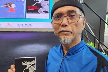 Penulis Abdul Manaf Abdul Kadir, bergambar dengan buku, ‘Kembar Pendekar’ (bahagian pertama), yang dilancarkan semasa Pesta Buku Melayu Singapura 2024 pada Ogos. 