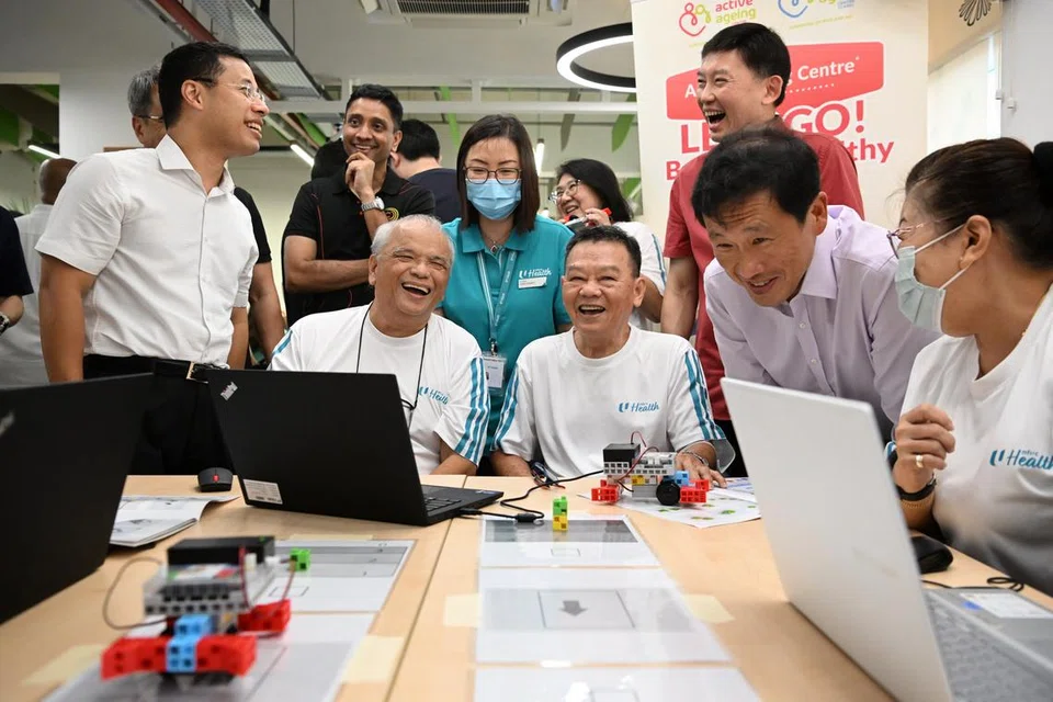 TINGKAT PERKHIDMATAN: Encik Desmond Lee (paling kiri),  Encik Ong Ye Kung (dua dari kanan), dan Encik Chee Hong Tat (belakang Encik Ong) menyertai program robotik dan pengekodan bersama warga emas di Pusat Penuaan Aktif Kesihatan NTUC, di Lengkok Bahru, semasa sidang media untuk mengumumkan butiran program Sihat Menua SG.