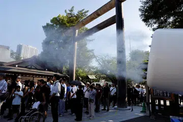 Orang ramai berdiri sambil disembur kabus air ketika menunggu untuk berdoa semasa lawatan mereka ke Kuil Yasukuni pada ulang tahun ke-80 penyerahan Jepun dalam Perang Dunia Kedua, di Tokyo, Jepun, 15 Ogos 2025.